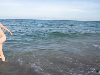 Голая девушка купается в море и веселится на пляже